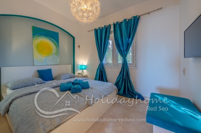 Schlafzimmer mit Doppelbett und Fernseher