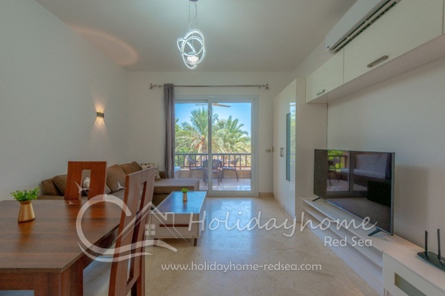 Wohnzimmer mit großen Smart TV und Zugang zum Balkon 