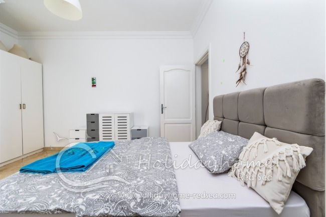 Gemüliches Bett mit Kissen. Kleiderschrank und Kommode.