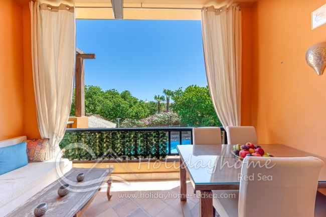 Balkon mit Sitzecke, Esstisch und Blick auf den Pool