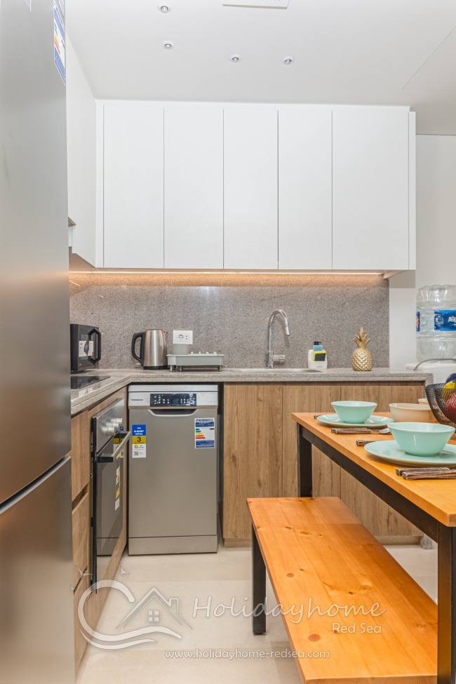 Voll ausgestattete K&uuml;che mit Sp&uuml;lmaschine, Backofen und Mikrowelle, sowie gro&szlig;em K&uuml;hlschrank und Wasserspender