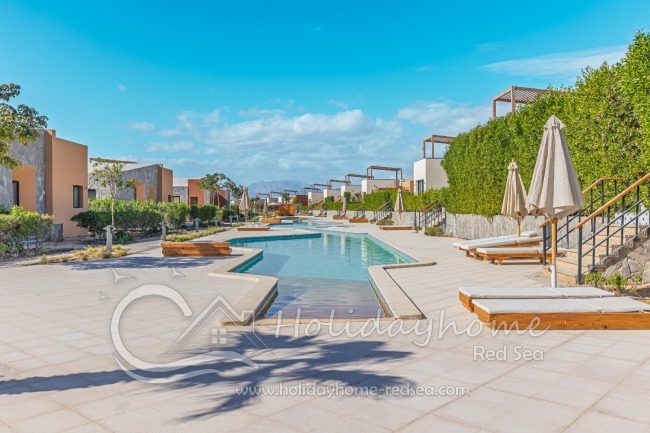 Gemeinschaftspool mit Sonnenliegen und Sonnenschirmen