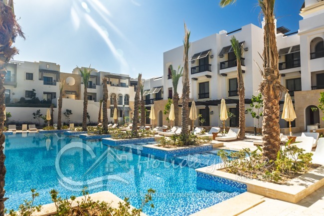 Gro&szlig;er Pool mit Sonnenliegen und Sonnenschirmen